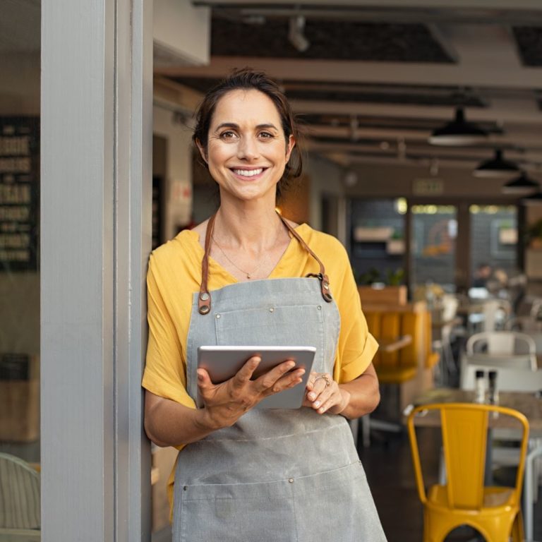 A worker at a small business holds an ipad ready to have her customer fill out a digital form.